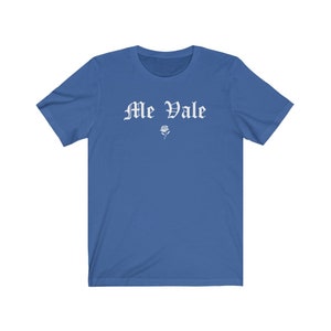 May include: A royal blue t-shirt with white text that reads "Me Vale" in a gothic font. A small white rose is below the text.