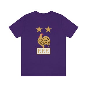 May include: Purple t-shirt with a gold rooster and two stars above it. The rooster is standing on a gold rectangle with the text "F.F.F."