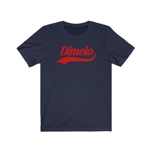 May include: A navy blue t-shirt with a red "Dimelo" graphic in a vintage baseball style font.