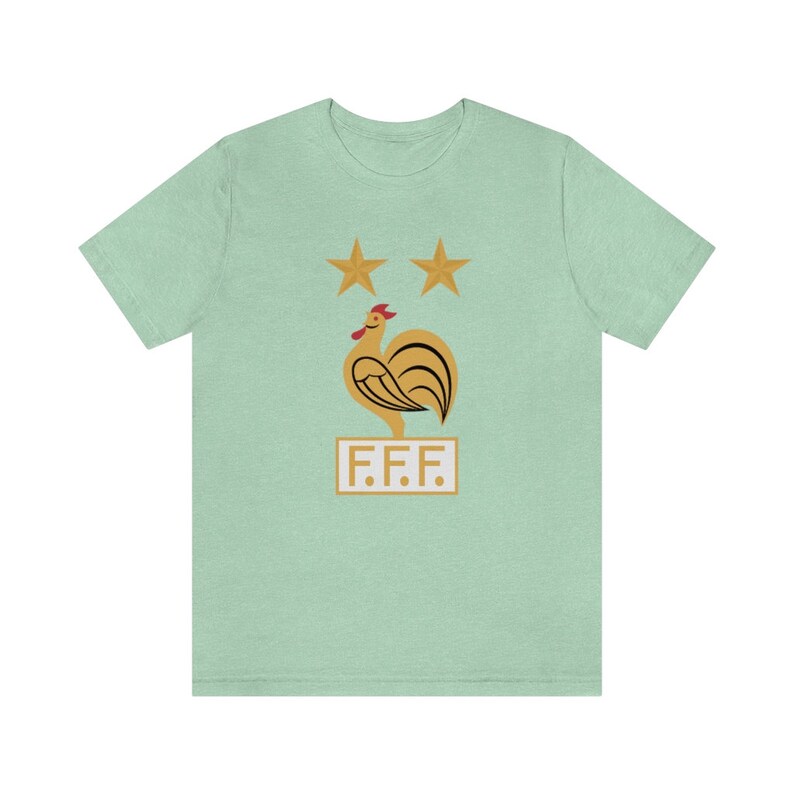 May include: A light green t-shirt with a gold rooster and two gold stars above it. The rooster is standing on a white rectangle with the text "F.F.F." in gold letters.