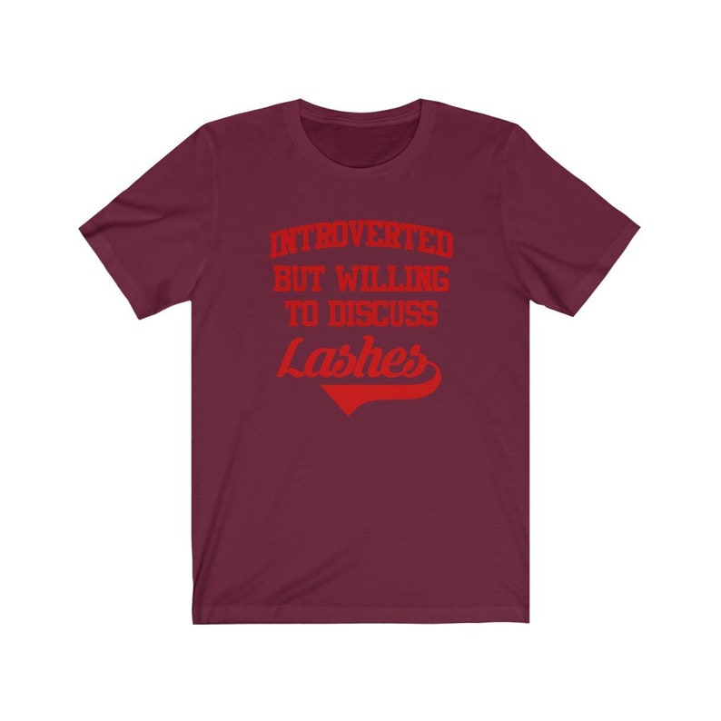 May include: Burgundy t-shirt with red text that reads "Introverted but willing to discuss Lashes".
