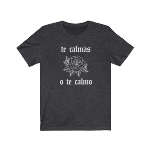 May include: Dark heather grey t-shirt with a white rose and the text "te calmas o te calmo" in a gothic font.