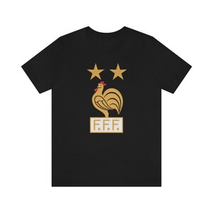 May include: Black t-shirt with a gold rooster and two stars above it. The rooster is standing on a white rectangle with the text "F.F.F." in gold letters.