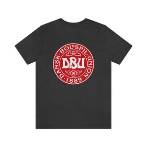 Puede incluir: Una camiseta gris oscuro jaspeada con un logotipo circular rojo que muestra el texto "Dansk Boldspil-Union DBU 1889".