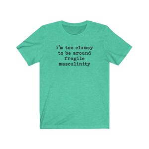 Puede incluir: Una camiseta verde turquesa con el texto "i'm too clumsy to be around fragile masculinity" impreso en negro.
