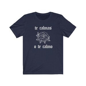 May include: Navy blue t-shirt with white text that reads "te calmas o te calmo" and a white rose graphic.