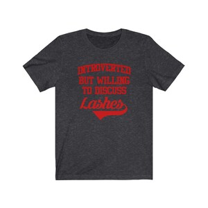 May include: Dark heather grey t-shirt with red text that reads "Introverted but willing to discuss Lashes".