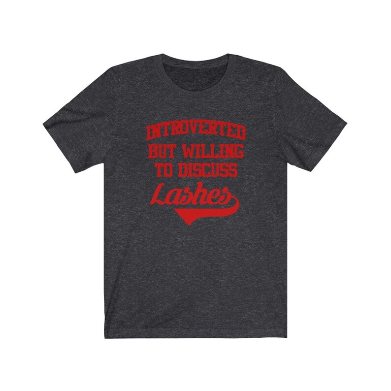 May include: Dark heather grey t-shirt with red text that reads "Introverted but willing to discuss Lashes".