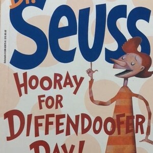 May include: A book cover featuring Dr. Seuss's "Hooray for Diffendoofer Day!" with some help from Jack Prelutsky & Lane Smith. The cover features a colorful illustration of a character with a striped orange and brown dress.