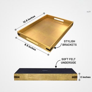 May include: Gold serving tray with black metal brackets and a soft felt underside. The tray measures 12.5 inches by 8.5 inches and is 2 inches tall.
