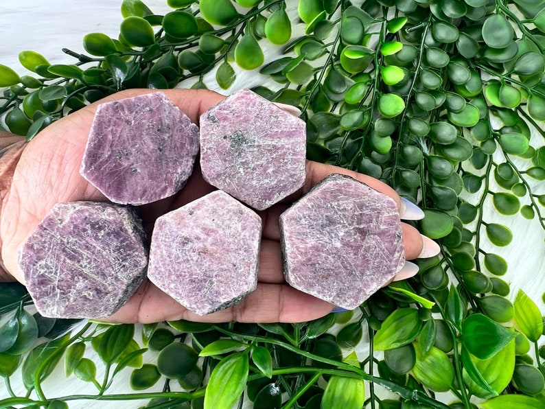 May include: Five pink ruby crystal points in a hexagonal shape. The crystals are raw and have a natural, rough texture.