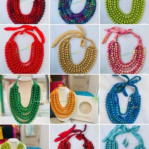 Könnte beinhalten: Eine Sammlung von bunten Holzperlenketten mit Seidenband-Bändern. Die Ketten sind in Rot, Grün, Blau, Gelb und Pink erhältlich.