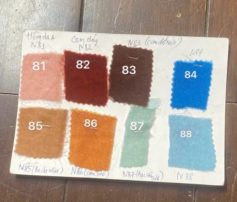 May include: A colour swatch card displaying nine fabric samples in different shades. The samples are numbered 81 to 88, with Vietnamese text. Colours include pink, red, brown, blue, orange, and green.