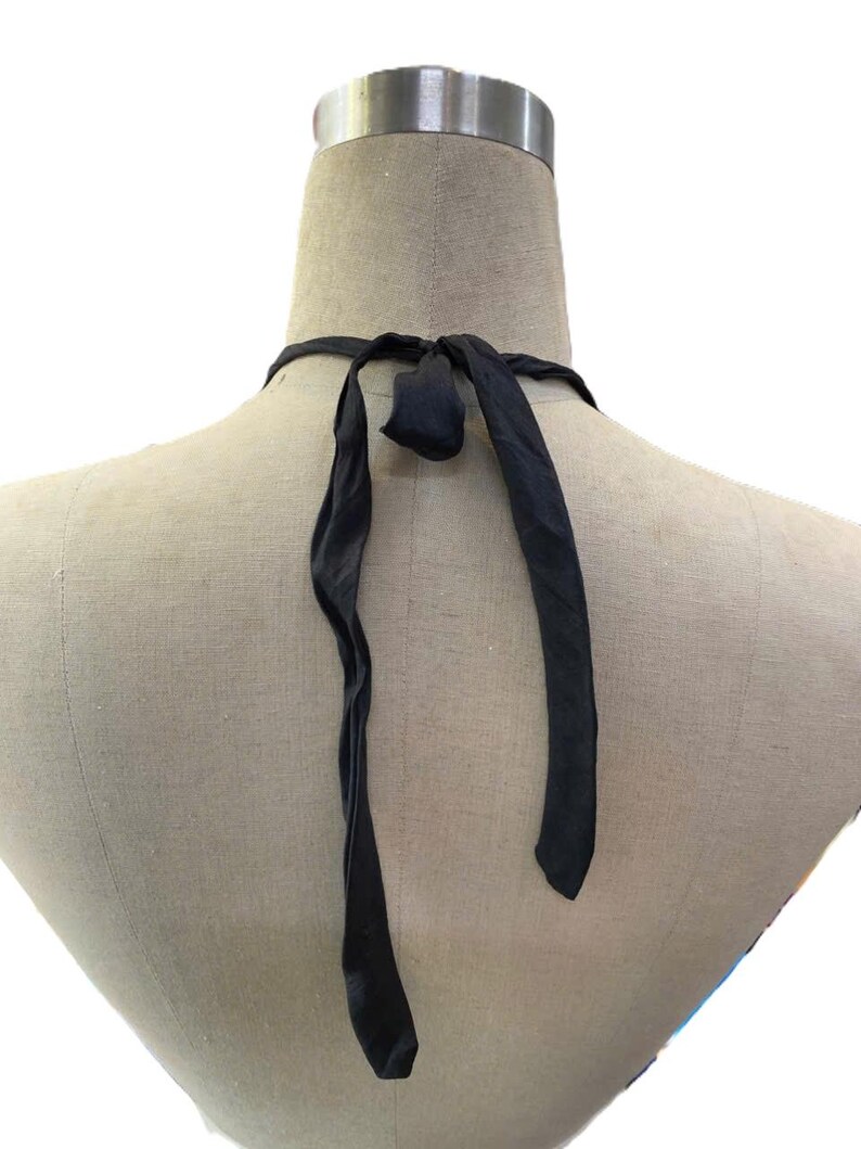 May include: A black halter top with long, flowing ties. The ties are knotted at the back of the neck. The top is displayed on a mannequin.