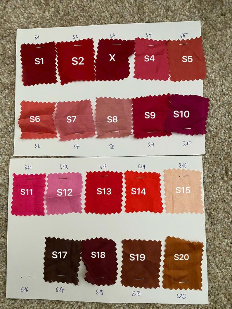 May include: A colour swatch chart displaying twenty fabric samples in shades of red, pink, and brown. Each sample is labelled with a number from S1 to S20. The samples are arranged on white paper.
