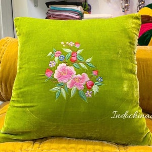 May include: A green velvet pillow with embroidered pink and white flowers. The pillow has the text "Indochina Silk" in the bottom right corner.