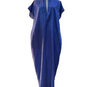 May include: A long, flowing blue dress with short sleeves and a mandarin collar. The dress has a deep V-neckline and a loose, comfortable fit. The fabric appears to be lightweight and slightly textured, creating a casual yet elegant look.