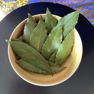 Op de afbeelding: Een kom gevuld met gedroogde laurierbladeren, een veelgebruikt kruid in de keuken om gerechten op smaak te brengen.
