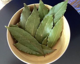 May include: A bowl filled with dried bay leaves, a common culinary herb used for flavoring dishes.