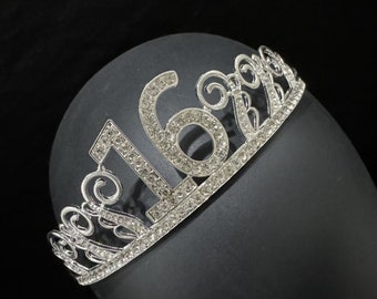 Könnte beinhalten: Silberne Tiara mit Strasssteinen, die die Zahl 16 trägt. Die Tiara ist für einen besonderen Anlass wie einen 16. Geburtstag gedacht.