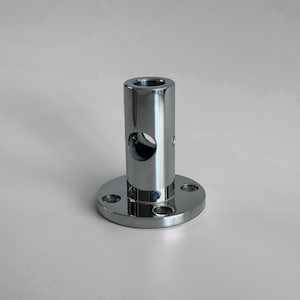May include: A silver metal pipe fitting with a round base and a hole in the centre of the pipe.