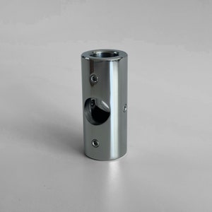 May include: A silver metal pipe fitting with a round hole in the center and four screw holes around the circumference.