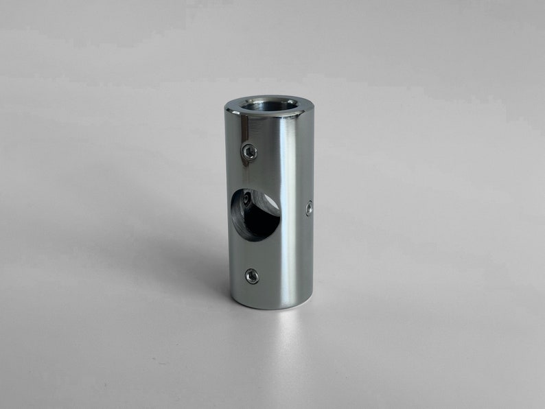 May include: A silver metal pipe fitting with a round hole in the center and four screw holes around the circumference.