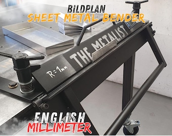 May include: Black sheet metal bender with a handle and wheels. The bender has a digital gauge and a label that reads "The Metalist". The bender is on a table with a metal tray and a piece of metal that has been bent.