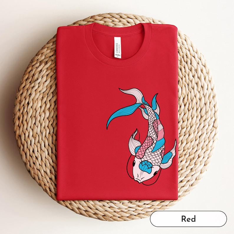 K&ouml;nnte beinhalten: Rotes T-Shirt mit einem bunten Koi-Fisch-Motiv. Der Fisch ist schwarz umrandet und hat rosa, blaue und wei&szlig;e Schuppen.