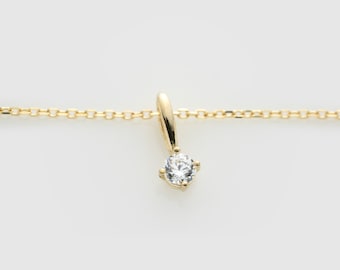 Può includere: Una delicata collana a catena d'oro con un ciondolo rotondo di diamante trasparente.