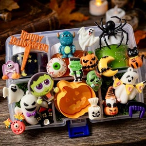 May include: A clear plastic organizer box filled with various Halloween-themed charms and miniature figures, including ghosts, a pumpkin, a black spider, a green monster, a skull, a crescent moon, and an orange sign reading Happy Halloween.