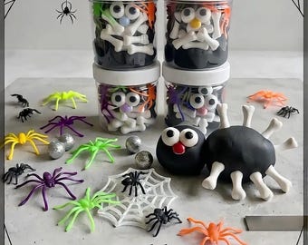 May include: A Build a Spider craft kit featuring four clear plastic jars with white lids filled with black modeling clay, white bone-shaped pieces, and googly eyes. Includes assorted plastic spiders in purple, green, yellow, and orange colors.