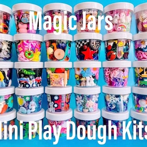 May include: A collection of thirty clear plastic jars with white lids, each filled with a variety of colorful miniature figurines and charms. The text Magic Jars and Mini Play Dough Kits is overlaid in white across the top and bottom of the image.