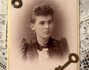 Conjunto de una tarjeta de gabinete de una niña victoriana con un colgante de corazón con un broche de llave y dos llaves esqueléticas vintage.