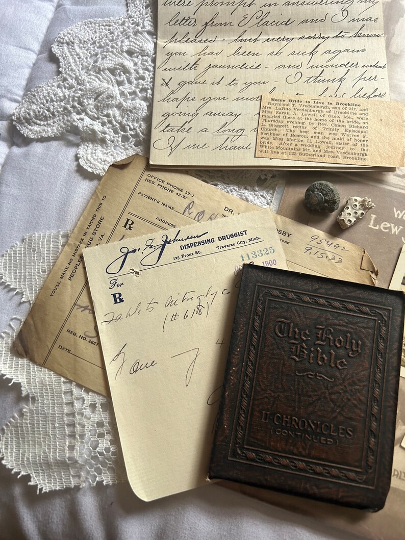 Puede incluir: Un libro antiguo encuadernado en cuero marr&oacute;n con el t&iacute;tulo "The Holy Bible" y "II Chronicles (Continued)" en relieve en la portada. El libro est&aacute; sobre una superficie blanca con un trozo de papel y una receta manuscrita.