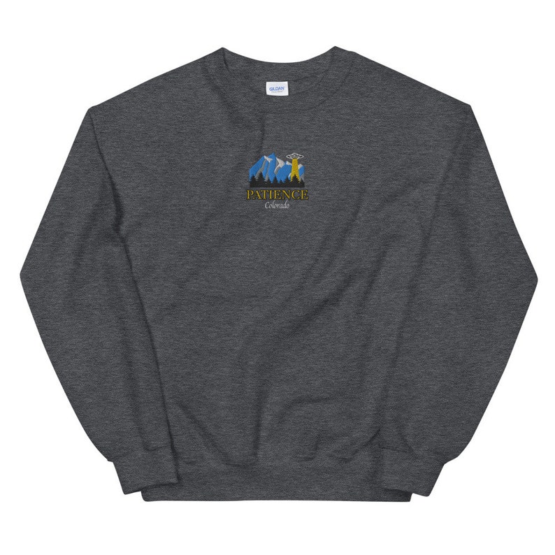 May include: Dark gray sweatshirt with a graphic of a mountain range and a UFO with the text "Patience Colorado" in gold lettering.