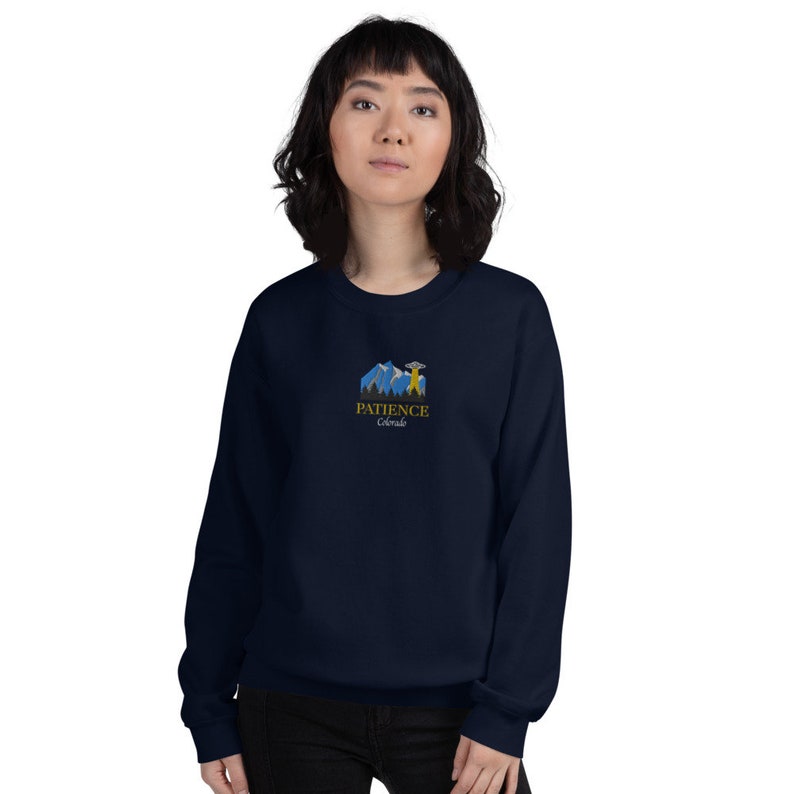 May include: A navy blue sweatshirt with a graphic of mountains, a UFO, and the text "PATIENCE Colorado".
