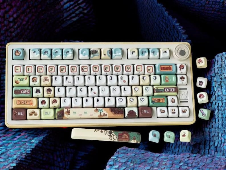 Op de afbeelding: Een cr&egrave;me mechanisch toetsenbord met aangepaste keycaps. De keycaps bevatten illustraties en tekst, waaronder cijfers, letters en symbolen. Het toetsenbord heeft een gele rand en een bijpassende polssteun. Extra keycaps liggen verspreid.