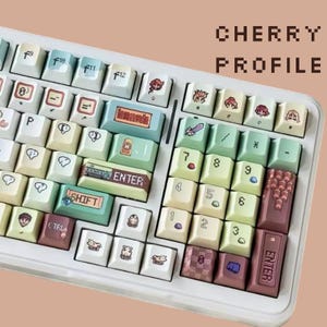 Op de afbeelding: Een wit mechanisch toetsenbord met aangepaste keycaps. De keycaps hebben een verscheidenheid aan pastelkleuren en unieke ontwerpen, waaronder stripfiguren en symbolen. De tekst "CHERRY PROFILE" wordt rechtsboven weergegeven.