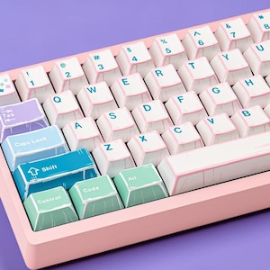 May include: A pink mechanical keyboard with white keycaps and light pink trim. The keys have blue lettering and some keys are pastel colors. The keyboard has a compact layout, with a variety of function keys and symbols.