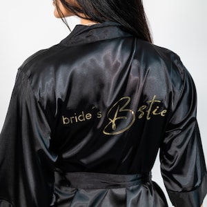 Könnte beinhalten: Schwarze Satin-Robe mit einer goldenen Aufschrift "bride's bestie".