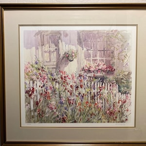 May include: Watercolor painting of a cottage with a white picket fence and vibrant flowers in shades of red, pink, and purple. The artwork is framed in a gold-colored frame.
