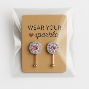 May include: A pair of pink and silver earrings with a clear plastic packaging and a card that says "Wear your sparkle" with a heart symbol.