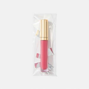 May include: A clear plastic bag containing a pink lip gloss with a gold cap.