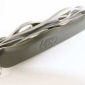 May include: A multi-tool with a dark green handle and multiple stainless steel blades. The tool includes a key ring and a logo on the handle. The blades are partially extended, showcasing the various functions.