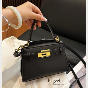May include: A black handbag with gold-coloured hardware and a clasp. It features a top handle and a detachable shoulder strap. The brand name "bagvella" is printed at the bottom, with the tagline "EVERYTHING FOR YOU".