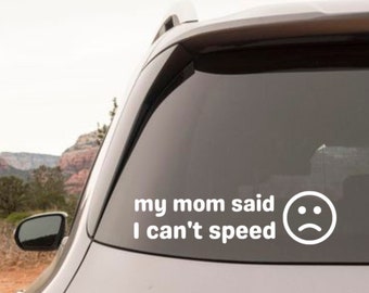 May include: A gray SUV with a white sticker on the back window that says "my mom said I can't speed" with a sad face emoji. The car has a GLB 250 emblem on the back.