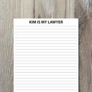 Könnte beinhalten: Ein weißer, linierter Notizblock mit dem Text "KIM IS MY LAWYER" oben.