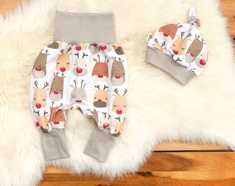 May include: A set of baby clothes featuring a white and gray color scheme with a reindeer print. The set includes a pair of gray and white pants with a fold-over waistband and a gray and white hat with a knot on top.