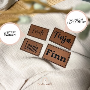 Könnte beinhalten: Vier braune Leder-Etiketten mit schwarzem Text. Die Etiketten lauten "Mats", "Finja", "Leonie" und "Finn". Der Text "Wunsch Text / Motiv" ist in weiß auf braunem Hintergrund in der oberen rechten Ecke des Bildes geschrieben.